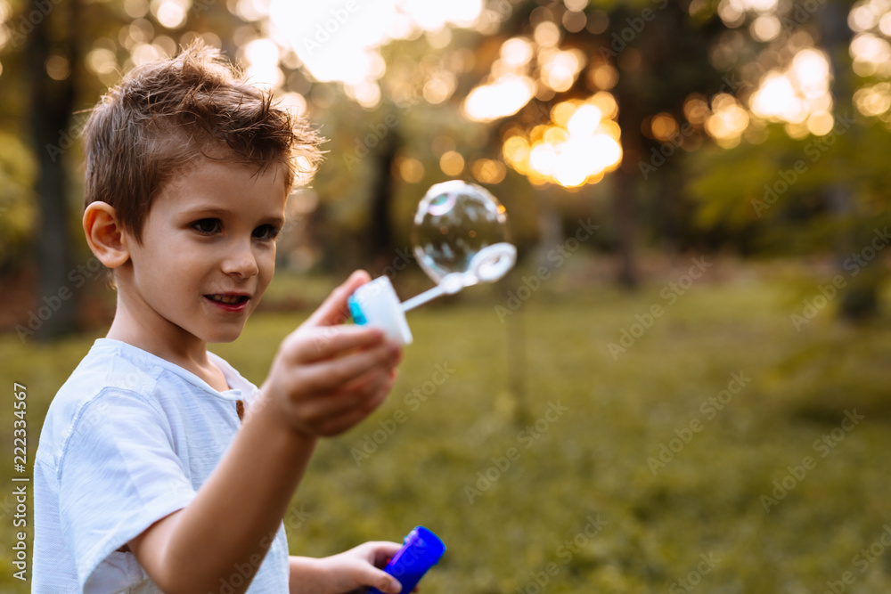 Little boy playing with soap balloons in park Little boy playing with soap balloons in park