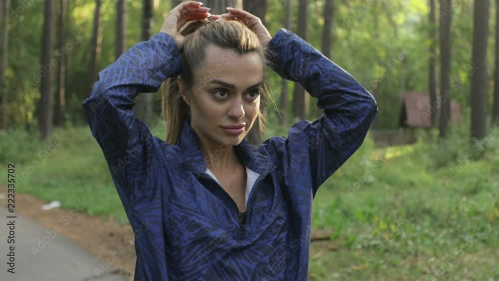 woman fixing her hair before running in the park