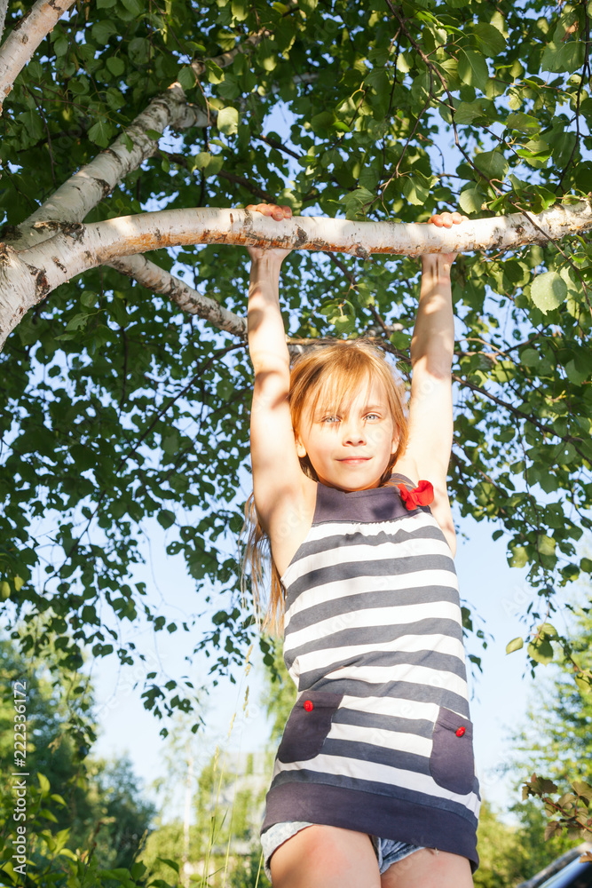 Happy girl hanging from a tree in a summer park Happy girl hanging from a tree in a summer park