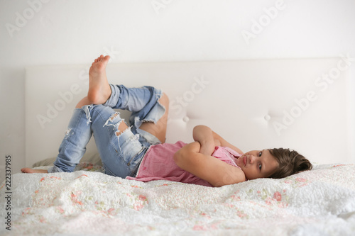 Girl child serious and frustrated sitting on bed photo