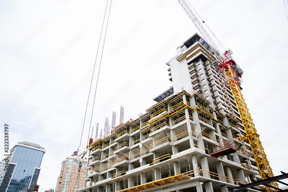 Construction site. Big industrial tower cranes with unfinished high raised buildings and blue