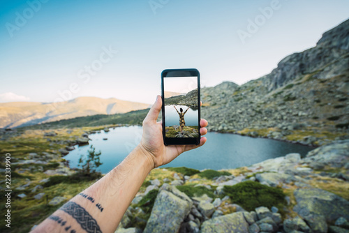 Crop man holding phone with picture in nature photo