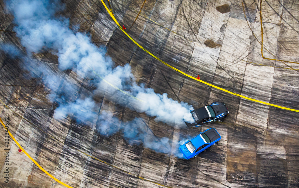 Aerial view from drone. Sport car wheel battle drifting. Blurred of image  diffusion race battle drift car with lots of smoke from burning tires on  speed track. Stock Photo