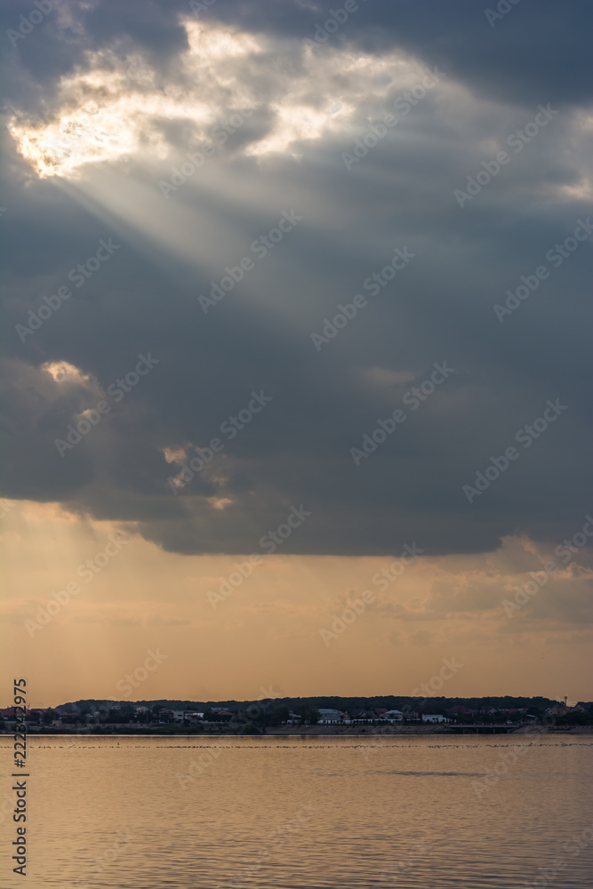 Beautiful Sun Rays Piercing the Grey Clouds and Falling on the Silent Lake