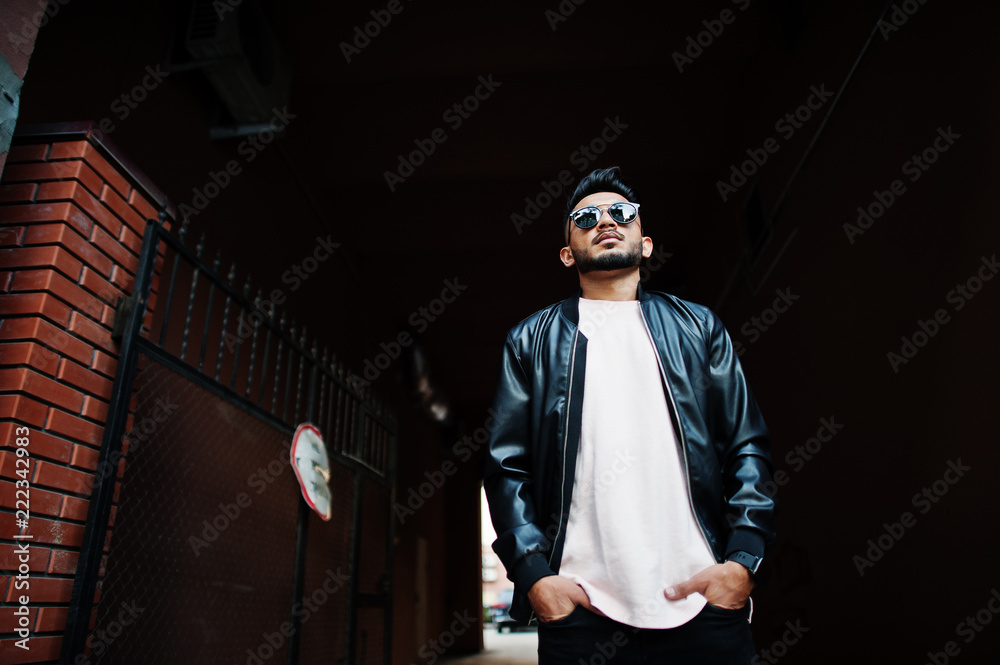 Stylish indian beard man at black leather jacket and sunglasses at tonnel arch. India model posed outdoor at streets of city. Stylish indian beard man at black leather jacket and sunglasses at tonnel arch. India model posed outdoor at streets of city.