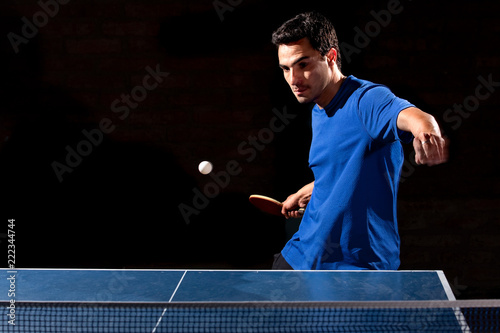 Deportista jugando tenis de mesa sobre fondo negro. photo