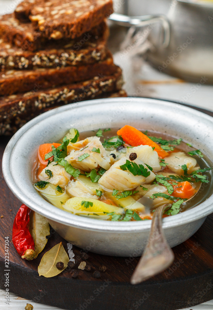 Fresh white fish soup with carrots, potatoes, onions, herbs and spices. Rustic style