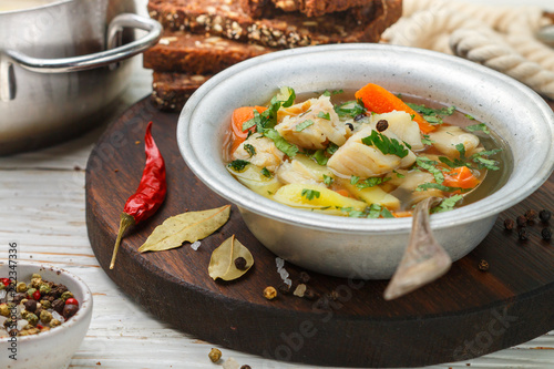 Fresh white fish soup with carrots, potatoes, onions, herbs and spices. Rustic style
