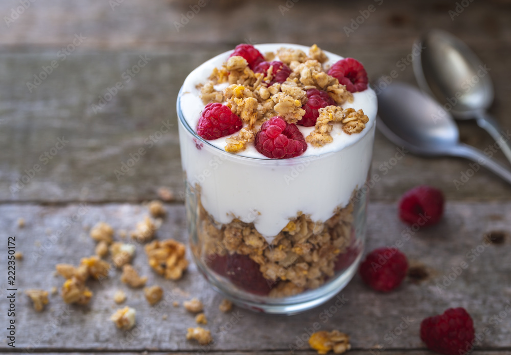 Yogurt with muesli in glass bowl with pieces raspberries on top. Yogurt with muesli in glass bowl with pieces raspberries on top.
