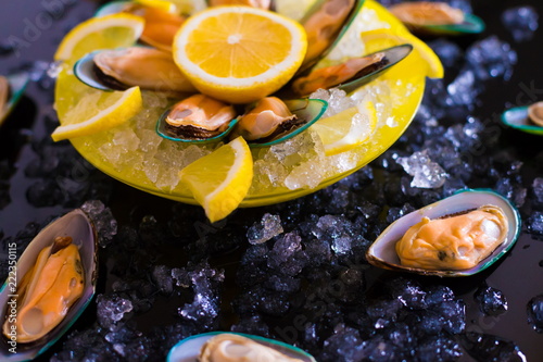 Food. mussels, vegetables, yellow plate, black background, ice