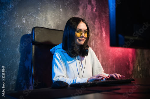 Beautiful Friendly Pro Gamer Girl Does Video Game Gameplay stream, Wearing Headset Talks and Chats with Her Fans and Team into Headphones Microphone. Teenagers Having Fun. Background Neon Retro Colors