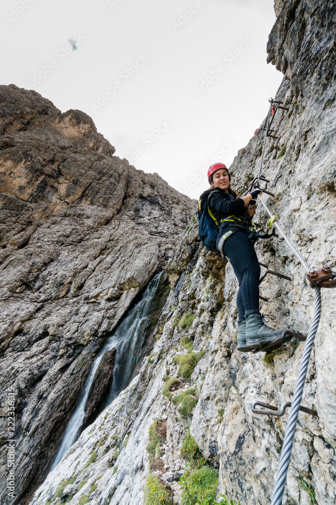 young attractive female mountain climber on a difficult Via Ferrata in the Dolomites in Alta Badia in the South Tyrol in Italy
