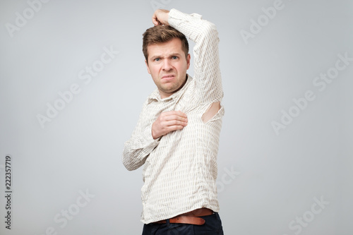 A young handsome man accidentally tore his shirt on his armpit.