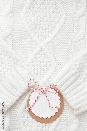 Festive white knitted winter sweater with a label for congratulations. Winter holidays. Vertikal