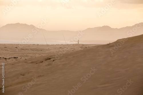 Fisherman Fishing in Sunset on Sand Dunes