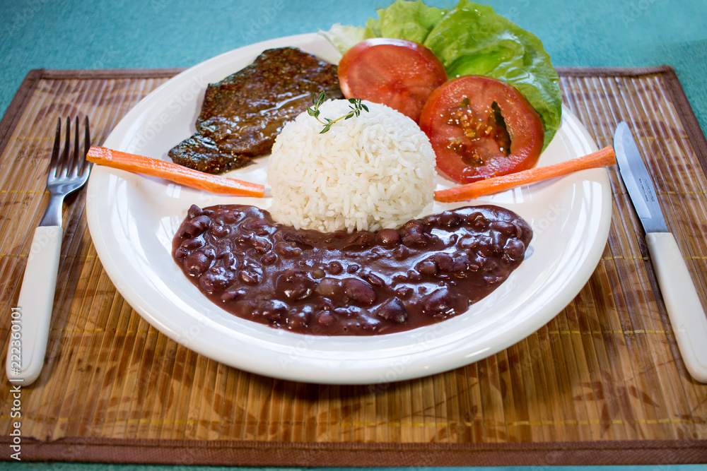Brasileirinho - Brazilian made typical dish of beans with rice with salad of lettuce, tomato and carrot and steak.