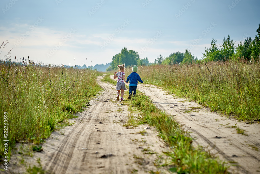 children hold hands and run on a country road