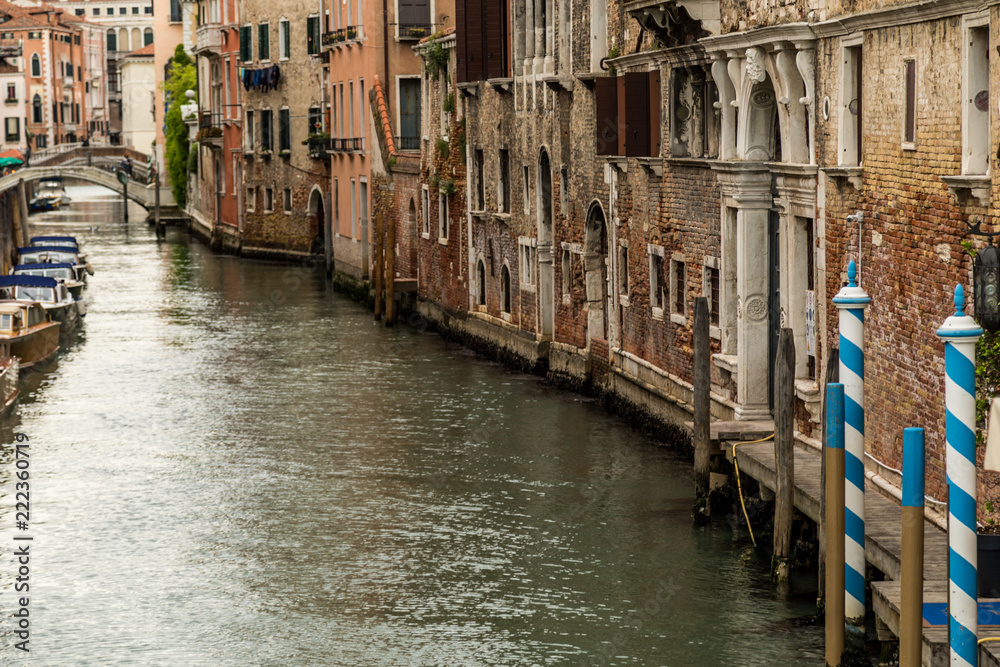 Fototapeta premium Wenecja, Włochy, miasto lagunowe, widok na stare alejki wzdłuż małych kanałów z zabytkowymi budynkami w słoneczny letni dzień.