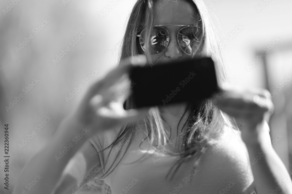 © Anna Jurkovska - Young woman with long hair in sunglasses and phone in hands