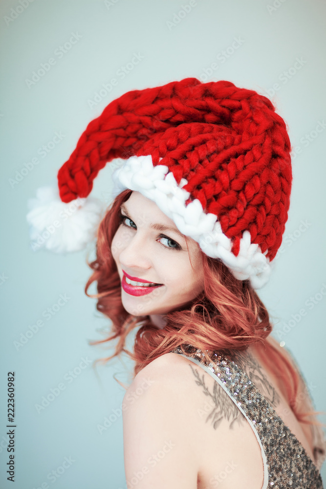 Santas little helper. Beautiful happy young woman with a santa claus hat, perfect make up, red lipstick, can be used as background Santas little helper. Beautiful happy young woman with a santa claus hat, perfect make up, red lipstick, can be used as background