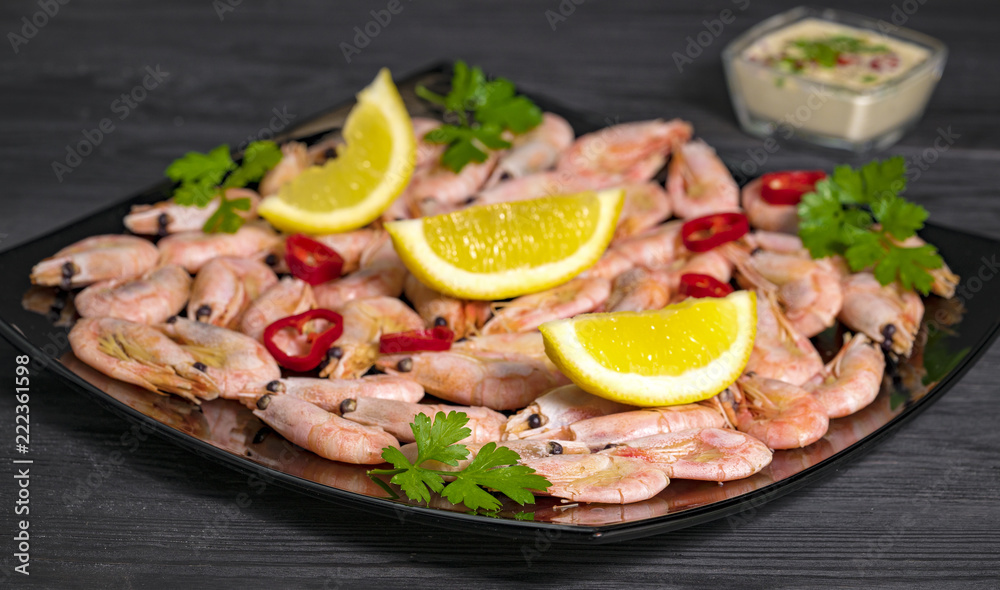 sauce and shrimp with pepper, lemon and greens on a black plate sauce and shrimp with pepper, lemon and greens on a black plate