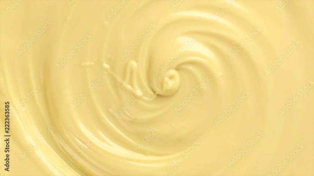 White molten chocolate swirl rotated background. Melted chocolate abstract curves backdrop. Creamy texture sweet rotation background close-up. Confectionery. 4K UHD video 3840x2160