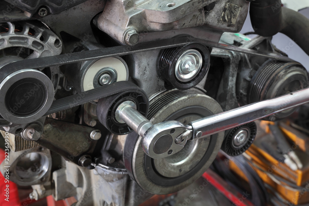 Pk belt, pulleys and alternator at modern car engine after servicing with ratchet tool