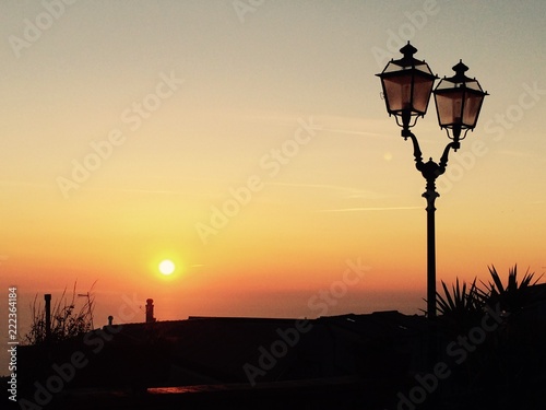 por do sol e poste de luz em uma praça