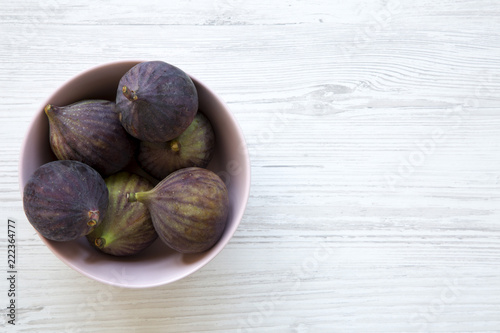 Fresh figs in a pink bowl on a white wooden table. Top view, overhead, from above. Copy space.