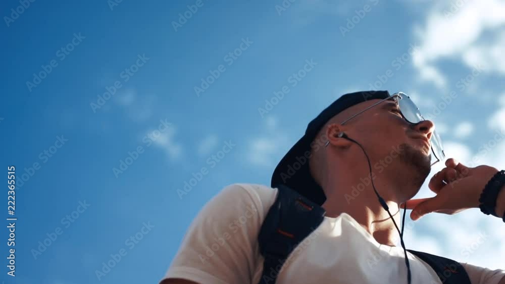 Young man dancing with headphones on the sky background Young man dancing with headphones on the sky background