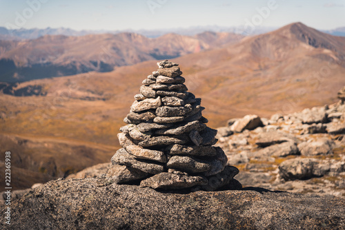 A large cairn marking a trail in Colorado with mountains in the background. 