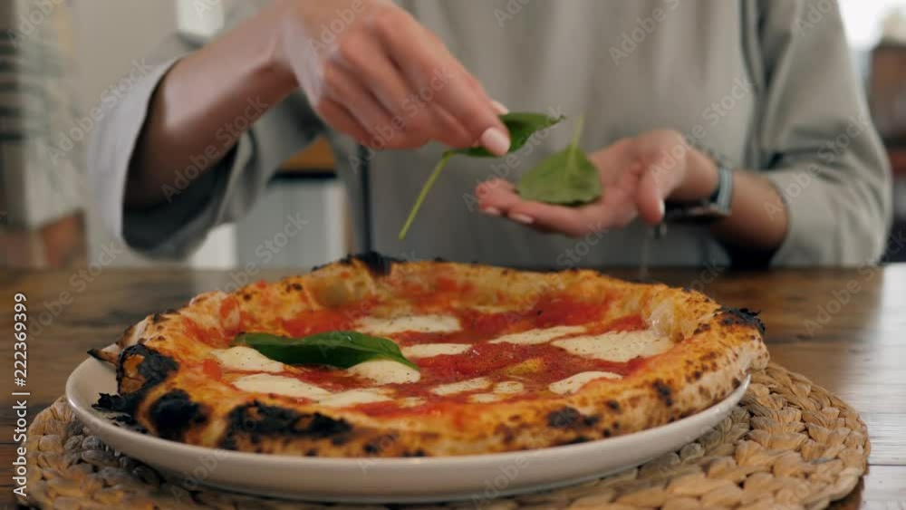 Chef in the pizzeria prepares a pizza and decorates it with parmesan cheese pepper and basil. Chef in the pizzeria prepares a pizza and decorates it with parmesan cheese pepper and basil.