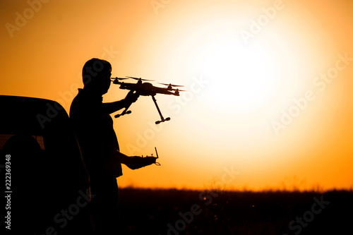 man holds a drone in the hands of the setting sun