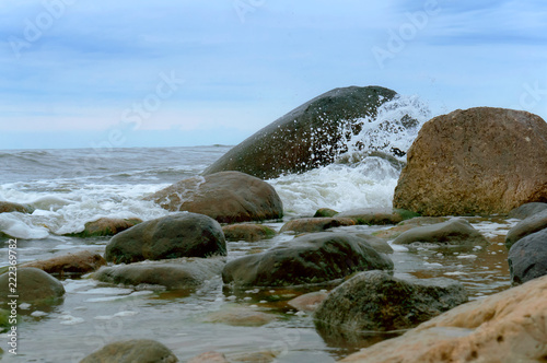 The wave breaks on the stones. Huge stones on the seashore.