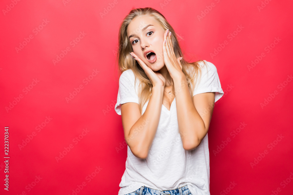 Portrait of happy screaming surprised young woman standing isolated over red background.