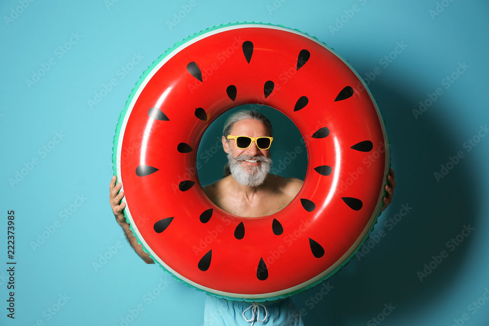 Naklejka premium Shirtless man with inflatable ring on color background