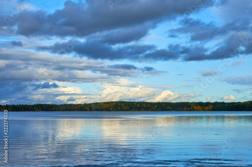 Sunset on the lake in autumn with cloudy sky and reflection in water. Natural background. © Arthur