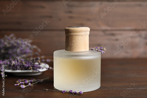 Fototapeta Naklejka Na Ścianę i Meble -  Bottle with aromatic lavender oil on wooden table