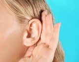 Young woman with hearing problem on color background, closeup