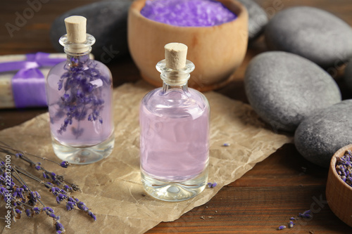 Fototapeta Naklejka Na Ścianę i Meble -  Bottles with natural herbal oil and lavender flowers on wooden background