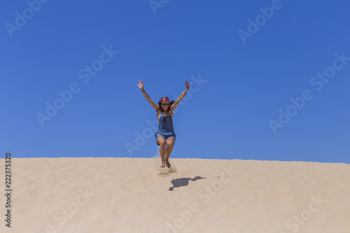 young beautiful woman jumping on the dunes in Portugal. Summertime, fun and holidays concept