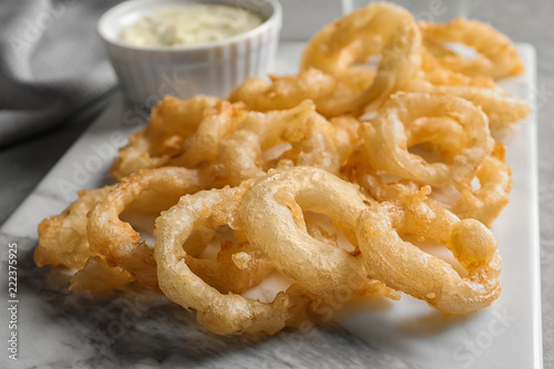 Closeup view of delicious golden breaded and deep fried crispy onion rings on marble board