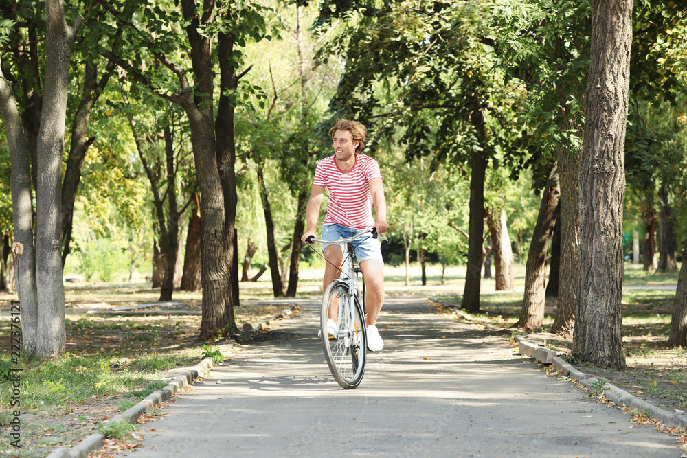 Handsome man riding bicycle in park on sunny day Handsome man riding bicycle in park on sunny day