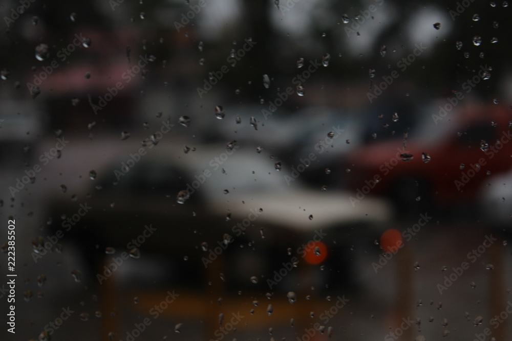 Vidrio rociado por lluvia con coches fuera