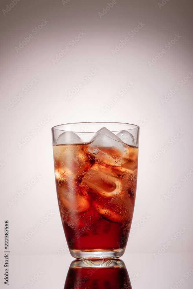 Cold glass of iced tea with ice cubes, grey background Cold glass of iced tea with ice cubes, grey background