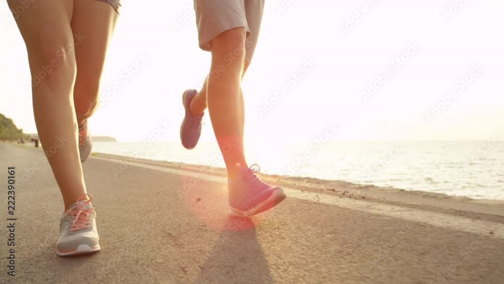 SUN FLARE, LOW ANGLE: Athletic male and female on summer vacation running along the picturesque coast in Slovenia. Unrecognizable fit young girlfriend and boyfriend jogging on a beautiful summer day. SUN FLARE, LOW ANGLE: Athletic male and female on summer vacation running along the picturesque coast in Slovenia. Unrecognizable fit young girlfriend and boyfriend jogging on a beautiful summer day.