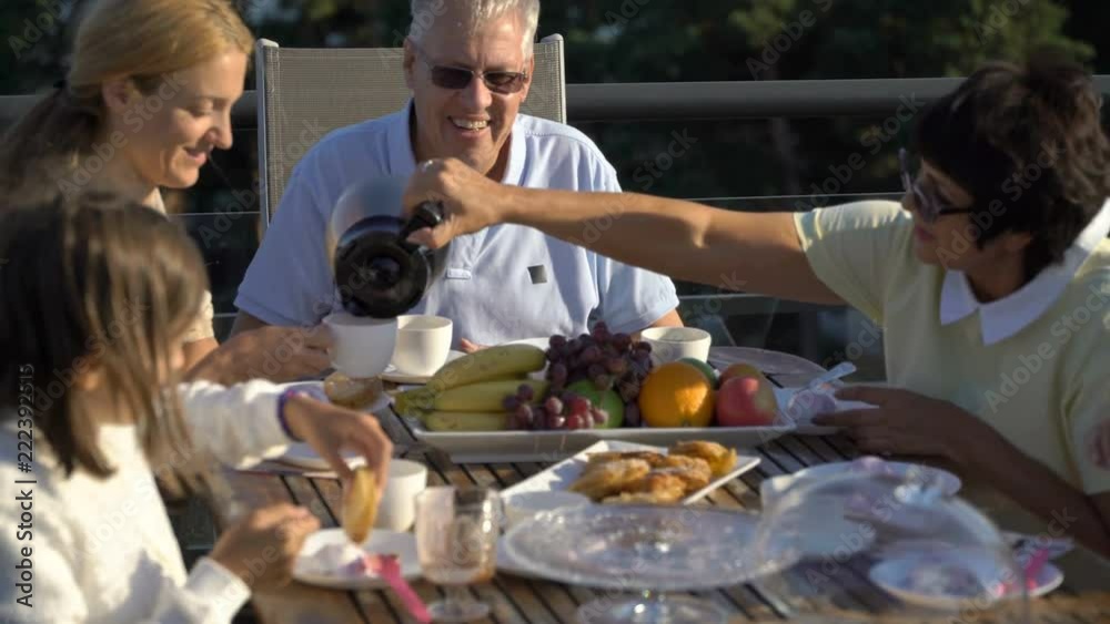 A big happy family has dinner on the open terrace on the roof of the house. Tea party on the summer terrace on the sea coast A big happy family has dinner on the open terrace on the roof of the house. Tea party on the summer terrace on the sea coast