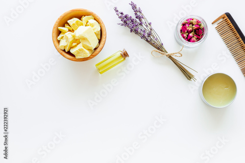 Hair treatment with natural products. Jojoba, argan, coconut oil near bunch of lavender and hairbrush on white background top view copy space