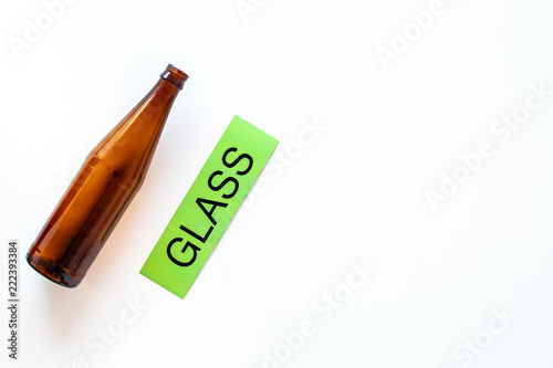 Types of matherial for reycle and reuse. Glass bottle near printed word glass on white background top view space for text photo