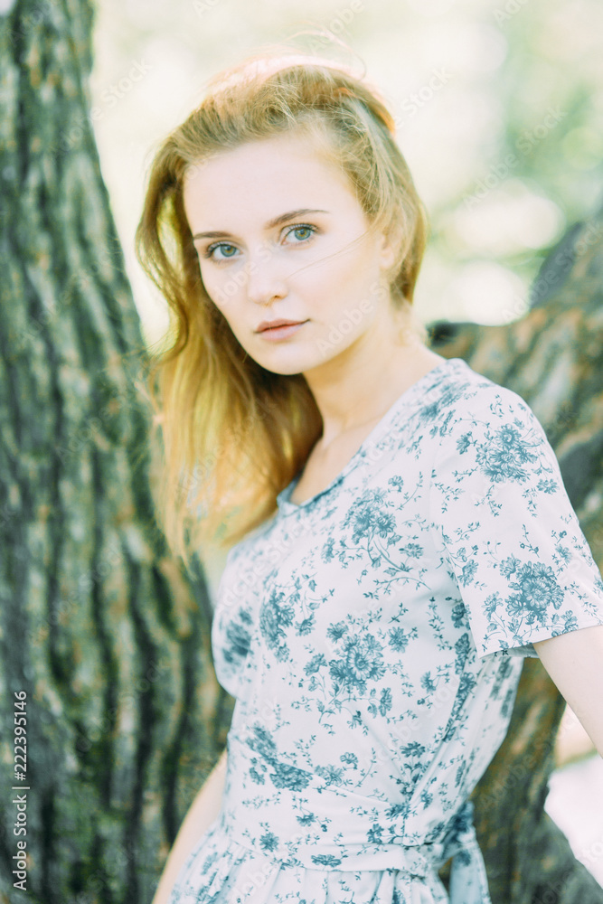 Naklejka premium beautiful girl in the Park, in a summer dress and walking. Smiles and enjoys nature. St. Petersburg, Yelagin island